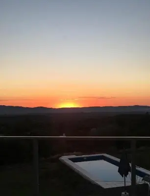 a sunset over a swimming pool on a balcony at Alta vista casa de campo Tanti in Tanti