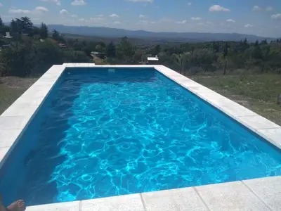 a large blue swimming pool with a view at Alta vista casa de campo Tanti in Tanti