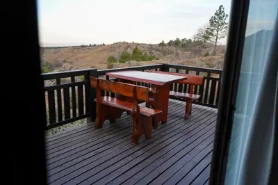 a wooden table and bench on a deck with a view at Refugio Alpino in La Cumbrecita