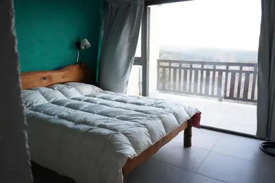 a bed in a room with a large window at Refugio Alpino in La Cumbrecita