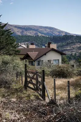 a fence in a field in front of a house at Refugio Alpino in La Cumbrecita