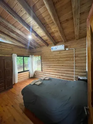 a bedroom with a bed in a room with wooden walls at Refugio Alpino in La Cumbrecita