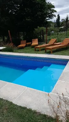 two benches and a pool with blue water at Cabañas Vista Ensueño in La Estancia