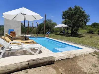 a swimming pool with two chairs and an umbrella at La soñada in Villa Santa Cruz del Lago