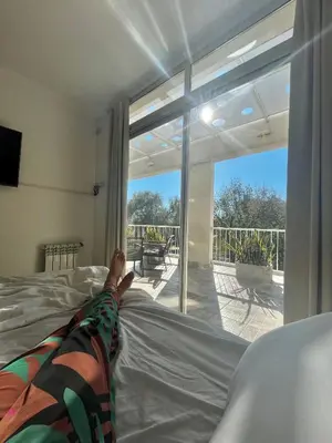 a person laying on a bed looking out a window at Departamento céntrico Terraza propia con vista a las montañas in Villa Carlos Paz