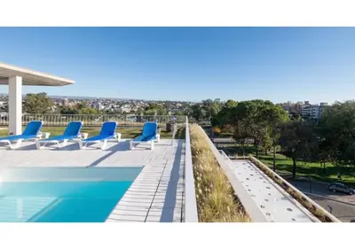 a view of a swimming pool with blue lounge chairs at Departamento céntrico Terraza propia con vista a las montañas in Villa Carlos Paz
