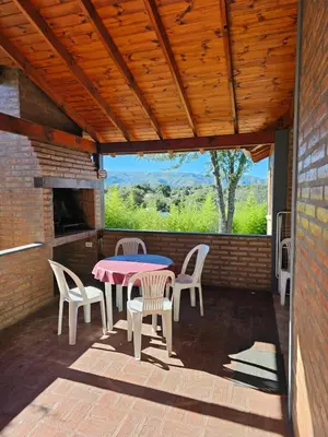 a patio with a table and chairs and a fireplace at Complejo Falda del Sauce in Villa General Belgrano