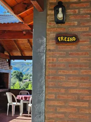 a sign on a brick wall with a table and chairs at Complejo Falda del Sauce in Villa General Belgrano