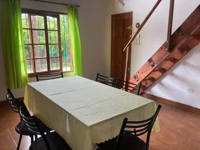 a dining room with a table with chairs and green curtains at Cabañas Onirico in Mina Clavero