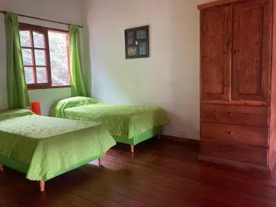 a bedroom with two beds and a dresser and a window at Cabañas Onirico in Mina Clavero