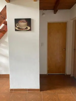 a white wall with a picture of a cup and a door at Cabañas Onirico in Mina Clavero