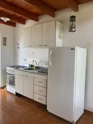 a kitchen with a white refrigerator and a stove at Cabañas Onirico in Mina Clavero