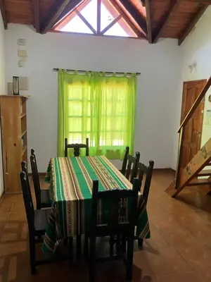 a dining room with a table and chairs and a window at Cabañas Onirico in Mina Clavero