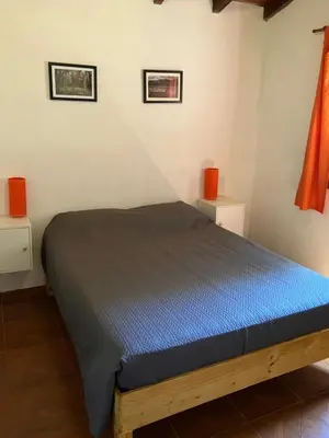 a bedroom with a bed with blue sheets and orange candles at Cabañas Onirico in Mina Clavero