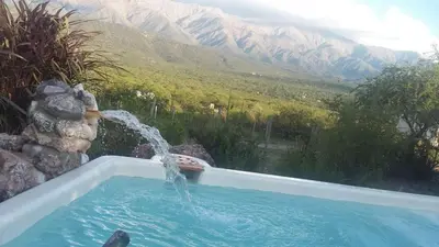 a pool with a water fountain in front of a mountain at Frente a la sierra in Quebrada de los Pozos