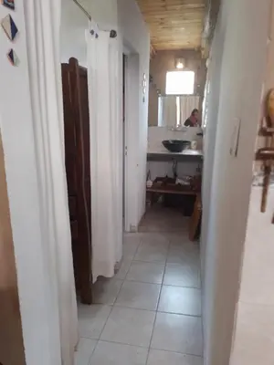 a hallway with white walls and a bathroom with a sink at Frente a la sierra in Quebrada de los Pozos