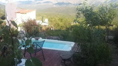 a swimming pool in a garden with mountains in the background at Frente a la sierra in Quebrada de los Pozos