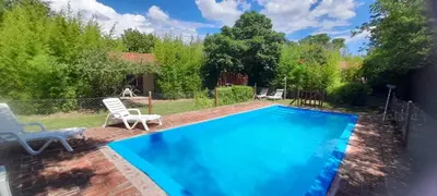 a small swimming pool with two chairs and a yard at Cabañas Rio de Oro in Mina Clavero