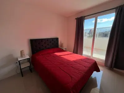 a bedroom with a red bed and a window at Departamento opera torre 3 in Villa Carlos Paz