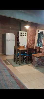 a kitchen with a wooden table and a refrigerator at Cabañas Rio de Oro in Mina Clavero