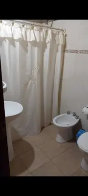 a bathroom with a white shower curtain and a toilet at Cabañas Rio de Oro in Mina Clavero