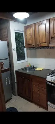 a kitchen with wooden cabinets and a sink and a refrigerator at Cabañas Rio de Oro in Mina Clavero