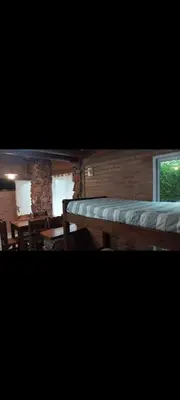 a room with a bed and tables and a window at Cabañas Rio de Oro in Mina Clavero