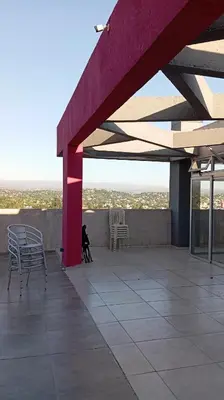 a cat sitting on a patio with chairs and a roof at Dept with pool and view in Villa Carlos Paz