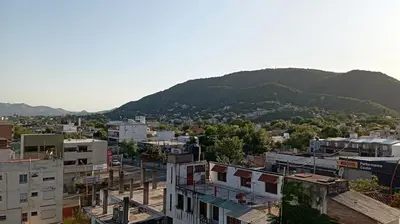 a city with buildings and a mountain in the background at Dept with pool and view in Villa Carlos Paz