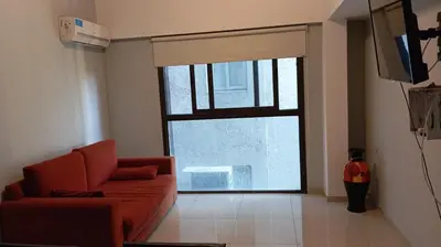a living room with a red couch and a large window at Dept with pool and view in Villa Carlos Paz