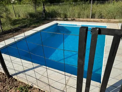 a blue swimming pool with a fence around it at Dos Eucaliptus in Villa Rumipal