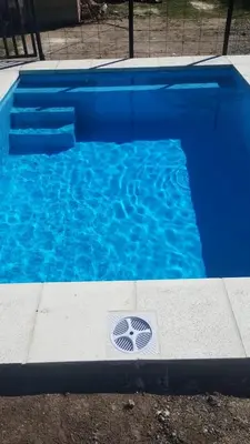 a blue swimming pool with a drain in the water at Dos Eucaliptus in Villa Rumipal