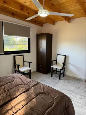 a bedroom with two chairs and a bed and a ceiling at Dos Eucaliptus in Villa Rumipal
