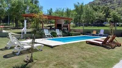 a backyard with a pool and chairs and a gazebo at Cabañas Casa Clara in Santa Rosa de Calamuchita