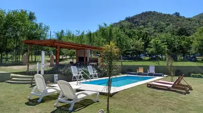 a swimming pool with chairs and a gazebo at Cabañas Casa Clara in Santa Rosa de Calamuchita