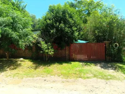 a brick fence with a red gate and trees at Casa jazmines in Villa Santa Cruz del Lago
