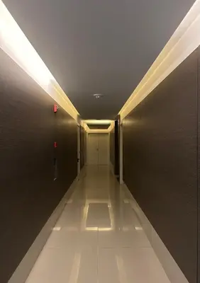 a hallway with a door and a white floor and lights at Apart France - Charmant Suites in Río Cuarto
