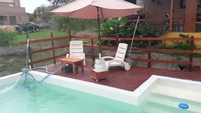 a deck with chairs and an umbrella next to a swimming pool at El Descanso cabaña in Cavalango