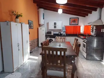 a kitchen with a wooden table and a kitchen with white appliances at El Descanso cabaña in Cavalango
