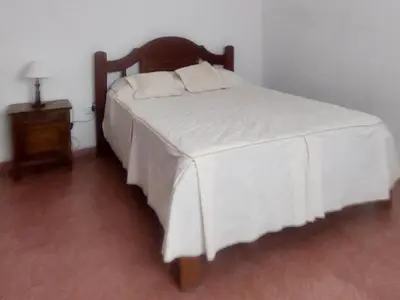 a bedroom with a white bed with a wooden headboard at La casa de Los Patitos in Arroyo de Los Patos