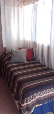 a bed with two pillows sitting in front of a window at Cabaña particular no complejo in Santa Rosa de Calamuchita