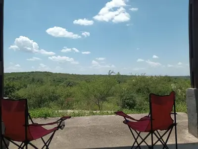 two red chairs sitting on a porch with a view at Tinkunaco Alta Gracia in Alta Gracia