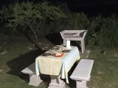 a picnic table and a chair in a yard at night at Tinkunaco Alta Gracia in Alta Gracia