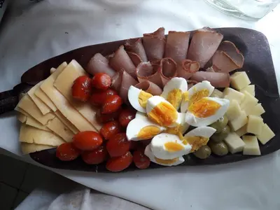 a plate of food with sausage eggs cheese and grapes at Tinkunaco Alta Gracia in Alta Gracia