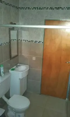 a bathroom with a toilet and a sink and a wooden door at Cabañas Qhawana in Carpintería