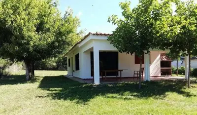 a small white house with a table in a field at Casa en Santa Rosa de Calamuchita in Santa Rosa de Calamuchita