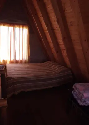 a bedroom with a bed in a attic with a window at Cabañas Alpinas M y M in Bialet Massé