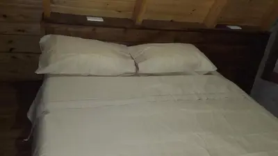 a white bed with two pillows on top of it at Cabañas Alpinas M y M in Bialet Massé