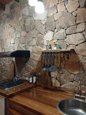 a kitchen with a stone wall with a sink and a counter at soy ahora in Pueblito