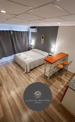 a bedroom with a bed and a desk and a table at Aparts Aldea Del Montañes in Mina Clavero